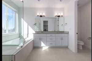 Bathroom with vanity, tiled bath, and toilet