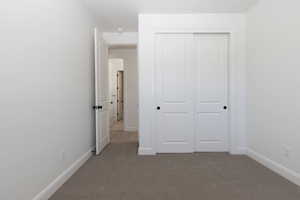 Unfurnished bedroom with light colored carpet and a closet