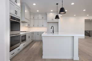 Kitchen featuring a kitchen island with sink, light wood-type flooring, and sink