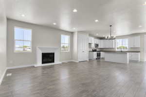 Unfurnished living room featuring a textured ceiling, light hardwood / wood-style flooring, an inviting chandelier, and sink