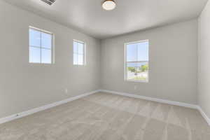 Empty room featuring light colored carpet and a textured ceiling