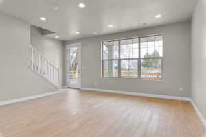 Spare room featuring light wood-type flooring and a healthy amount of sunlight