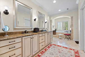 Bathroom featuring vanity, ornamental molding, tile patterned floors, and a relaxing tiled tub