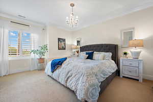 Carpeted bedroom featuring crown molding and an inviting chandelier