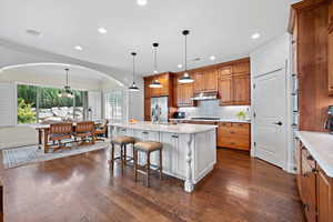 Kitchen featuring plenty of natural light, decorative light fixtures, an island with sink, and dark hardwood / wood-style floors