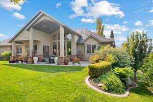 Back of house with a lawn and a patio