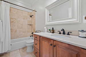 Full bathroom with vanity, toilet, ornamental molding, tile patterned floors, and shower / bathtub combination with curtain