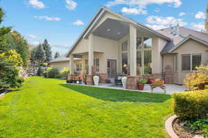 Rear view of house with a yard and a patio