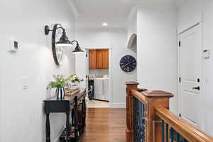 Hall featuring ornamental molding, wood-type flooring, and washer and dryer