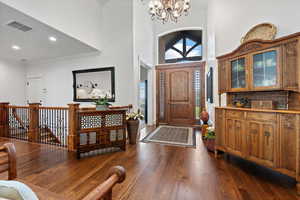 Foyer entrance featuring dark hardwood / wood-style floors, an inviting chandelier, crown molding, and a towering ceiling