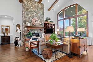 Living room with dark wood-type flooring, beam ceiling, and a fireplace