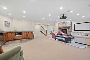 Living room with crown molding, light carpet, and a stone fireplace