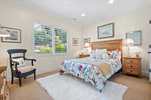 Bedroom with ornamental molding and light carpet