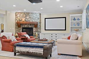 Carpeted home theater featuring crown molding and a stone fireplace