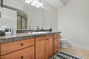 Bathroom featuring ornamental molding, vanity, toilet, and a shower with shower door