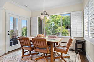 Dining space featuring a notable chandelier, wood-type flooring, and crown molding