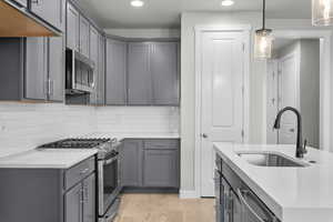 Kitchen featuring light hardwood / wood-style flooring, decorative light fixtures, stainless steel appliances, sink, and gray cabinets