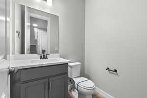 Bathroom with hardwood / wood-style floors, toilet, and vanity