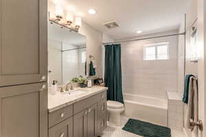 Full bathroom with tile patterned floors, toilet, shower / bath combo with shower curtain, and vanity