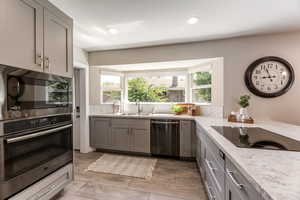 Kitchen featuring light stone countertops, stainless steel appliances, tasteful backsplash, and sink