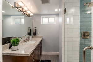 Bathroom featuring vanity, hardwood / wood-style flooring, and a tile shower