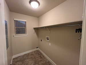 Clothes washing area featuring hookup for a washing machine, electric dryer hookup, and a textured ceiling