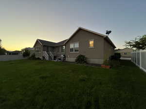 Back house at dusk with a yard