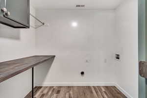 Clothes washing area featuring washer hookup, electric dryer hookup, light hardwood / wood-style floors, and cabinets