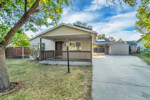 View of front of property featuring a front yard, covered porch, and a storage unit