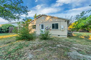 Rear view of property with cooling unit and a lawn