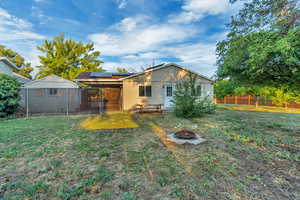 Rear view of property with a yard and an outdoor fire pit