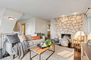 Living room with hardwood / wood-style floors and a stone fireplace