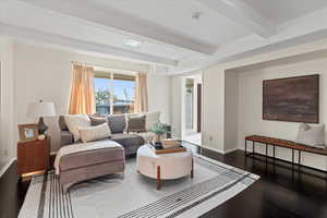 Living room with dark hardwood / wood-style floors and beam ceiling