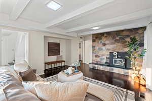 Living room with hardwood / wood-style flooring, beam ceiling, and a wood stove