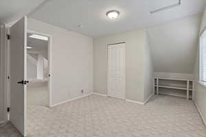 Additional living space with vaulted ceiling and light colored carpet