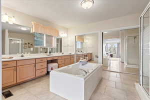 Bathroom featuring tile patterned floors, separate shower and tub, and vanity