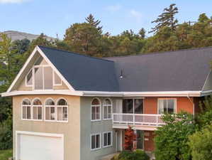 View of front of house with a balcony, a Valley view, a garage, and a front lawn