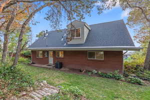 Rear view of property featuring cooling unit and a lawn