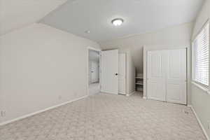 Unfurnished bedroom with light carpet, lofted ceiling, and a closet