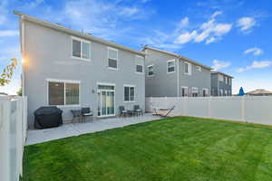 Rear view of property with a lawn and a patio area