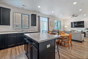 Kitchen with a kitchen breakfast bar, a kitchen island, sink, ceiling fan, and hardwood / wood-style flooring