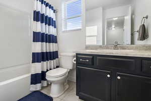 Full bathroom with vanity, toilet, shower / tub combo, and tile patterned floors