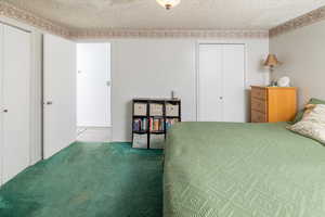 Carpeted bedroom featuring a textured ceiling and two closets