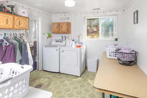 Clothes washing area featuring cabinets and washing machine and dryer