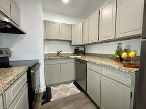 Kitchen featuring hardwood / wood-style flooring, sink, light stone countertops, and stainless steel appliances