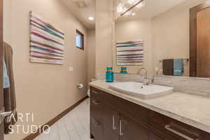 Bathroom featuring vanity, toilet, and backsplash