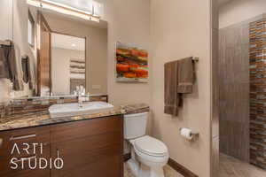 Bathroom featuring tile patterned floors, tiled shower, toilet, and vanity