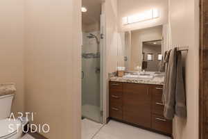 Bathroom featuring a shower with shower door, toilet, vanity, and tile patterned floors