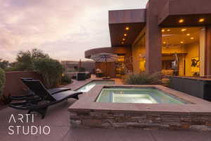 Pool at dusk with an in ground hot tub and a patio area