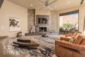 Living room featuring ceiling fan and a stone fireplace